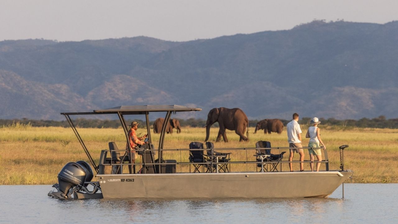 Safari boat cruising past Lake Kariba with elephants in background