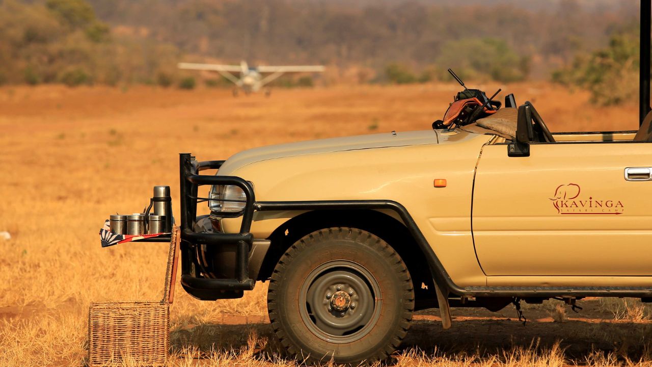 Safari vehicle at private airstrip as charter plane arrives Zimbabwe