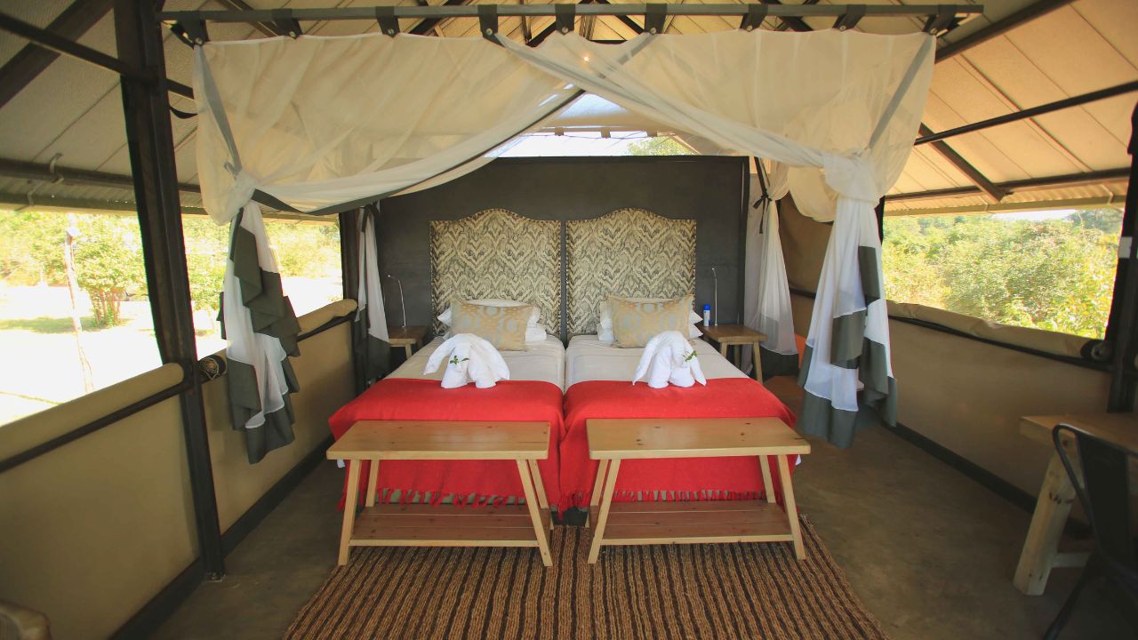 Twin beds with white and red linen in guest room, Kavinga Camp