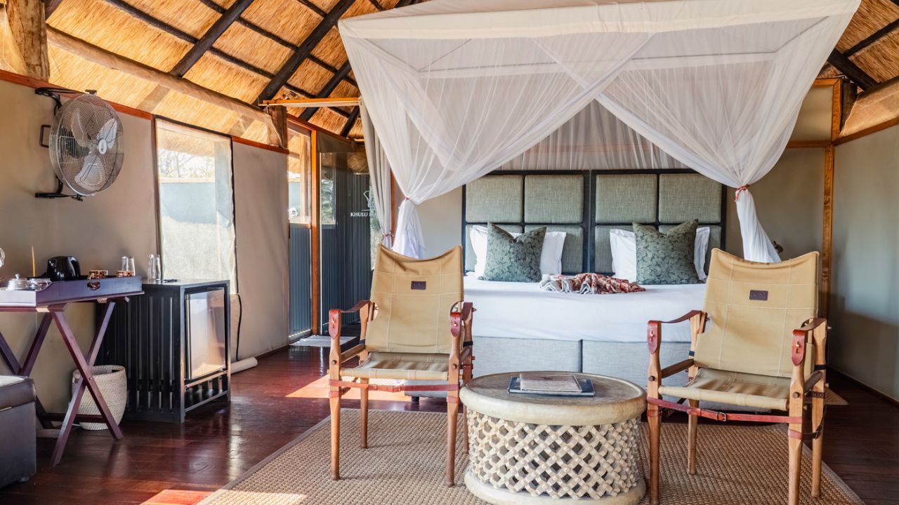 Double bed with mosquito net and green-white pillows at Kulu Bush Camp