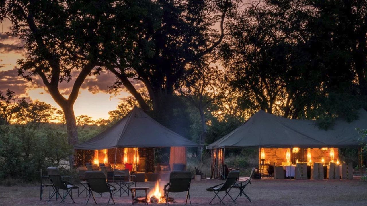 Tents and campfire at sunset at Hwange Bush Camp, Hwange National Park, Zimbabwe.