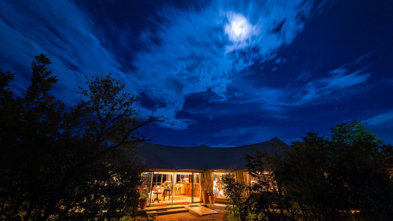 The Elephant Camp lodge lit at night under full moon, Victoria Falls