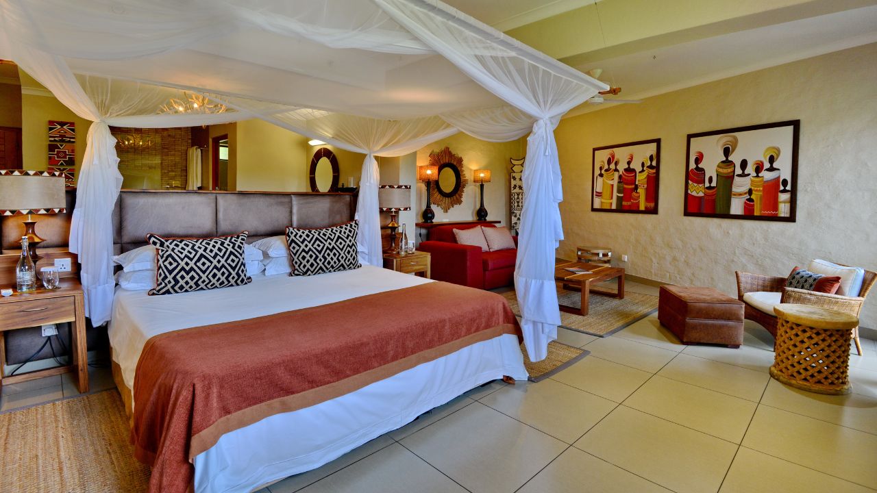 Double guest suite at Victoria Falls Safari Club with mosquito net, beige room, red blankets