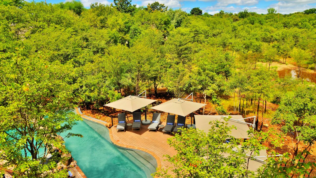 Aerial view of swimming pool and shaded lounge areas at Victoria Falls Safari Club