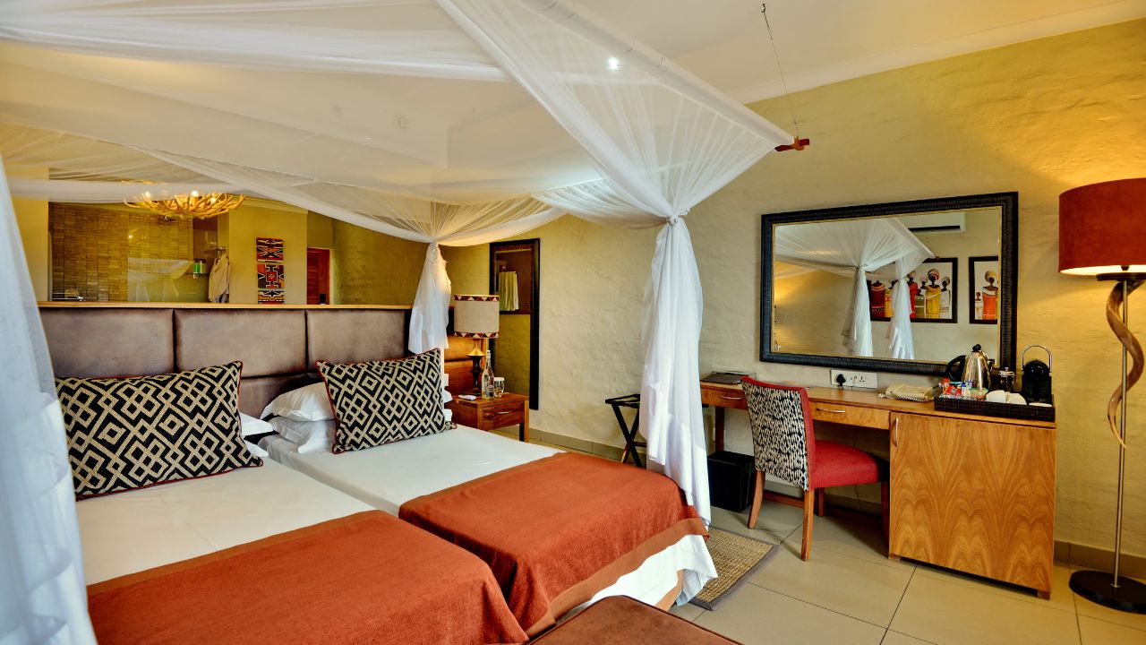 Double guest room at Victoria Falls Safari Club with mosquito net and red blankets