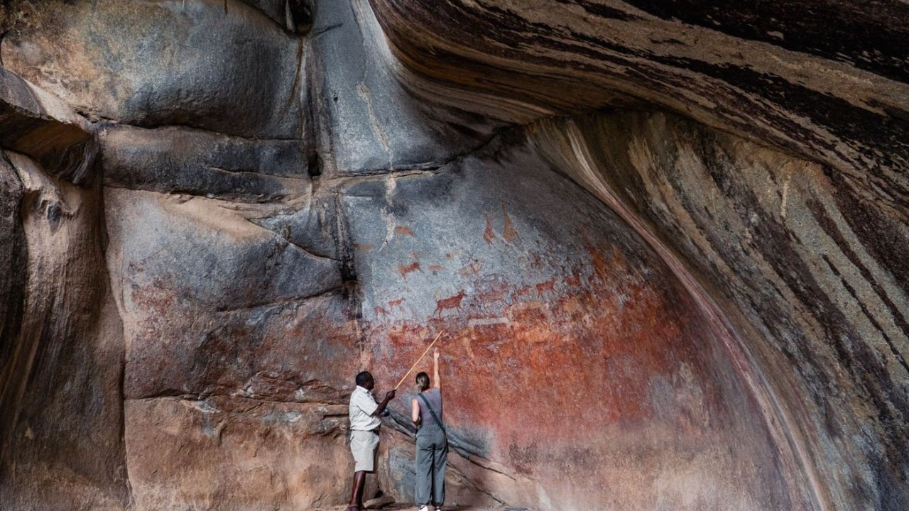 Safari guide explains rock paintings to guests in Matobo National Park
