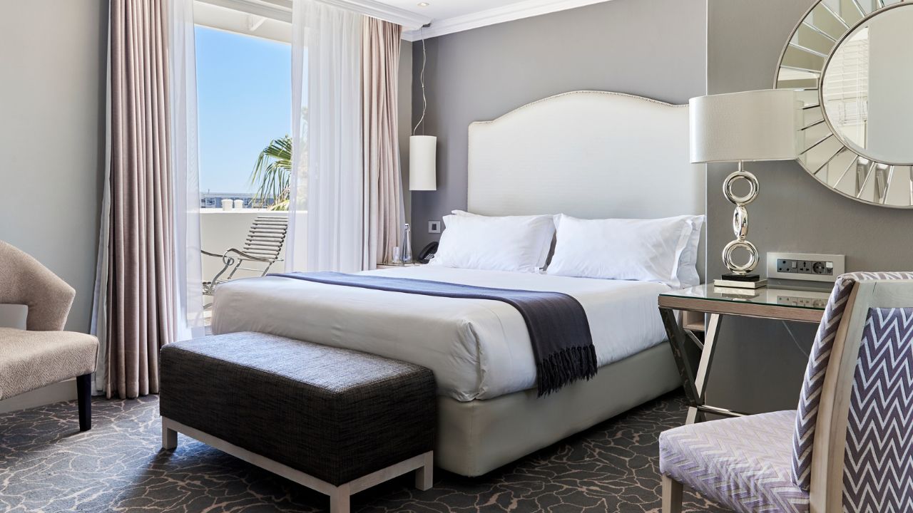 Junior suite with double bed and white linens at Queen Victoria Hotel.