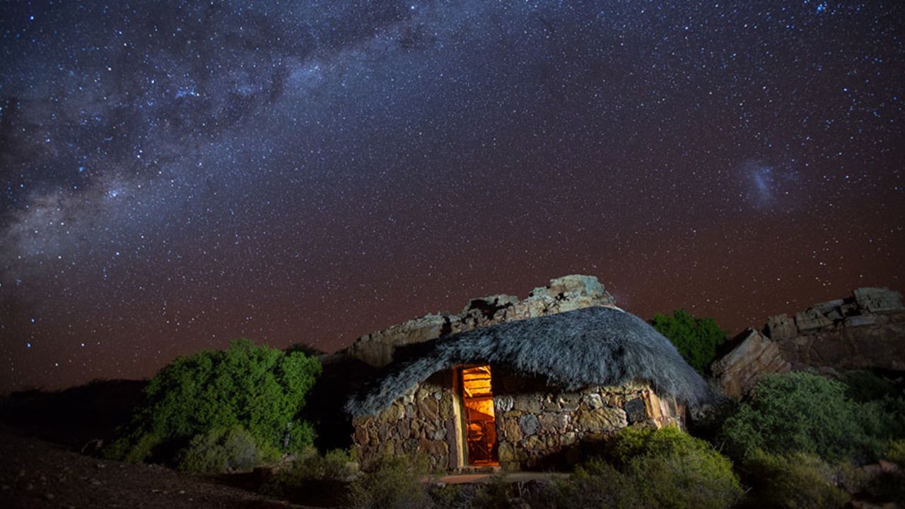 Thatched stone house under starry night sky in Bakkrans Cederberg.