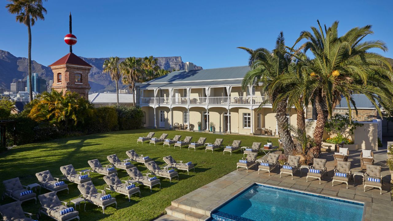 Swimming pool and lawn area with Deck House Hotel and Table Mountain.