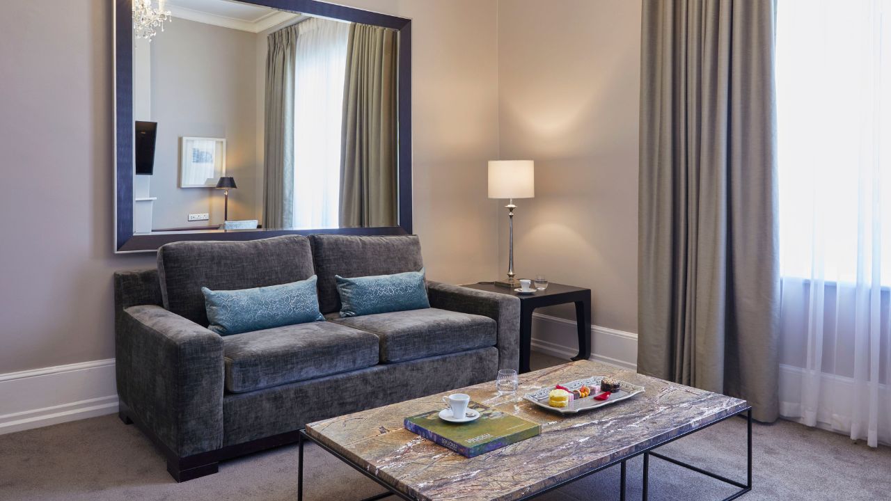 Luxury suite lounge area with chair, mirror, and table Dock House Hotel.