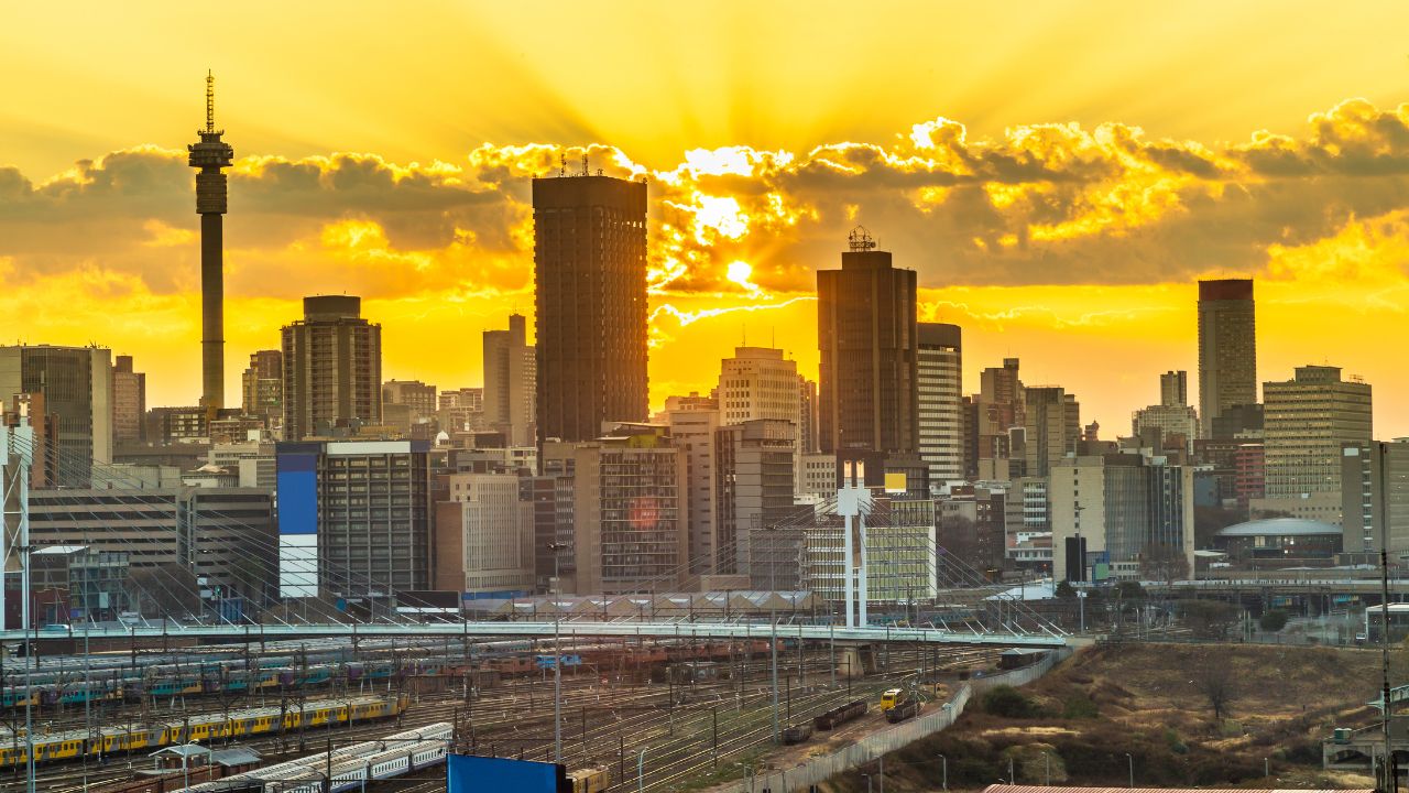 Golden sunset behind Johannesburg skyline with Nelson Mandela Bridge foreground.