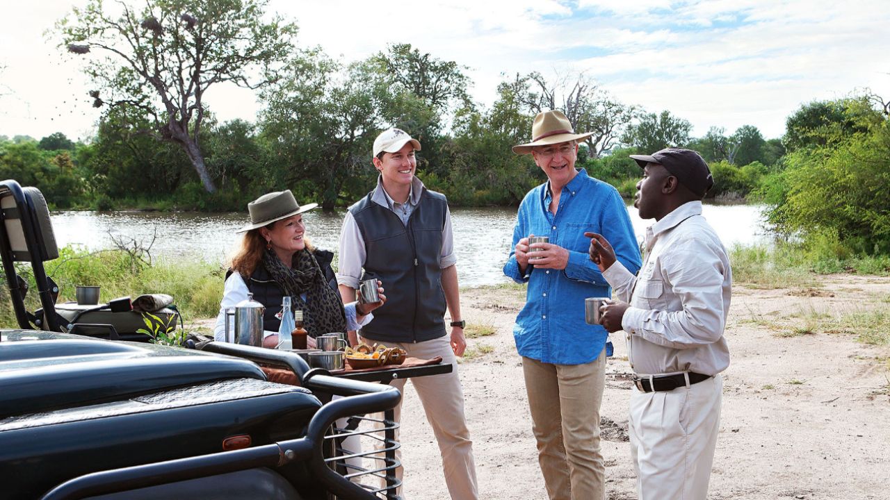 Ranger and three guests enjoy riverside drinks on safari at Londolozi.