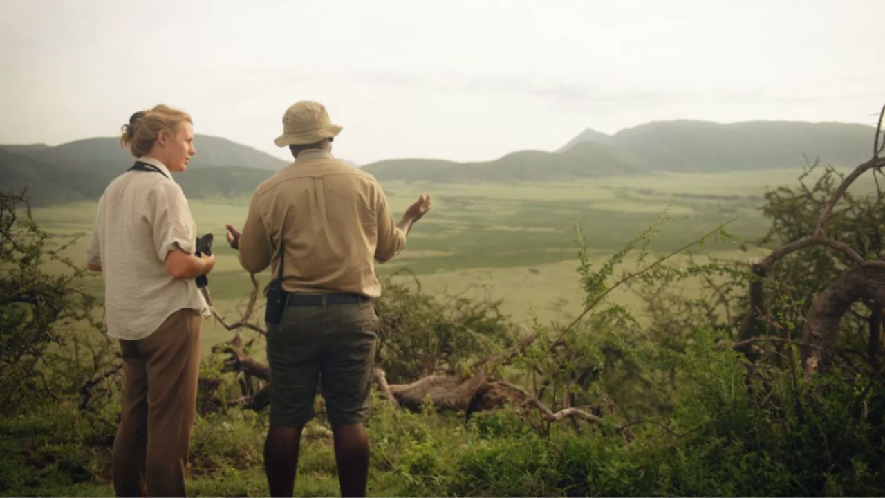 Safari guests speaking with a ranger while overlooking the vast Serengeti plains.