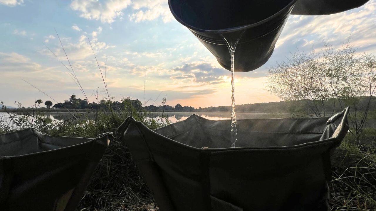Pouring hot water from a bucket for a shower at the camp, close-up view.