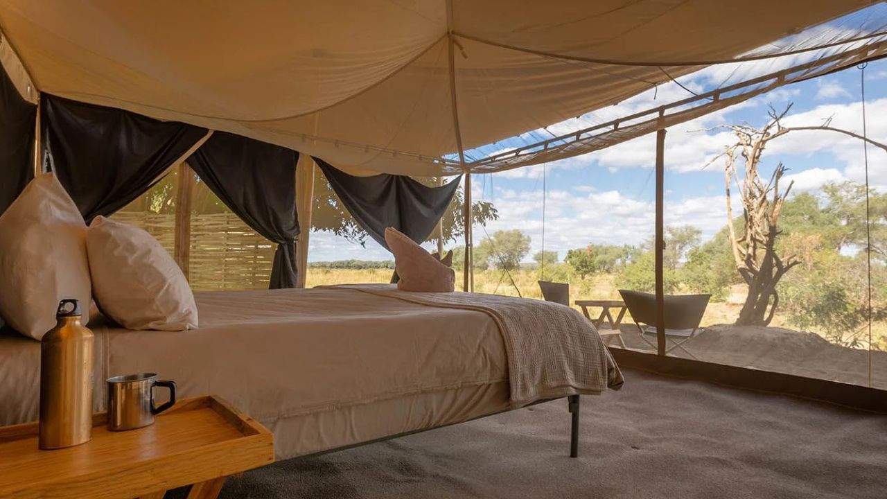 Inside Chula Island Camp tent, looking across double bed through mosquito netting at bush in background, Zambia.