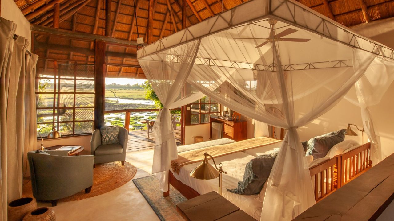 Guest accommodation with thatched roof and mosquito netting, view from back of room looking out to bush.