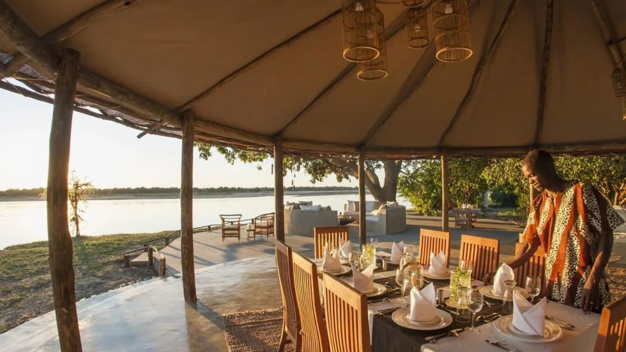 General dining area outdoors under thatch roof overlooking river