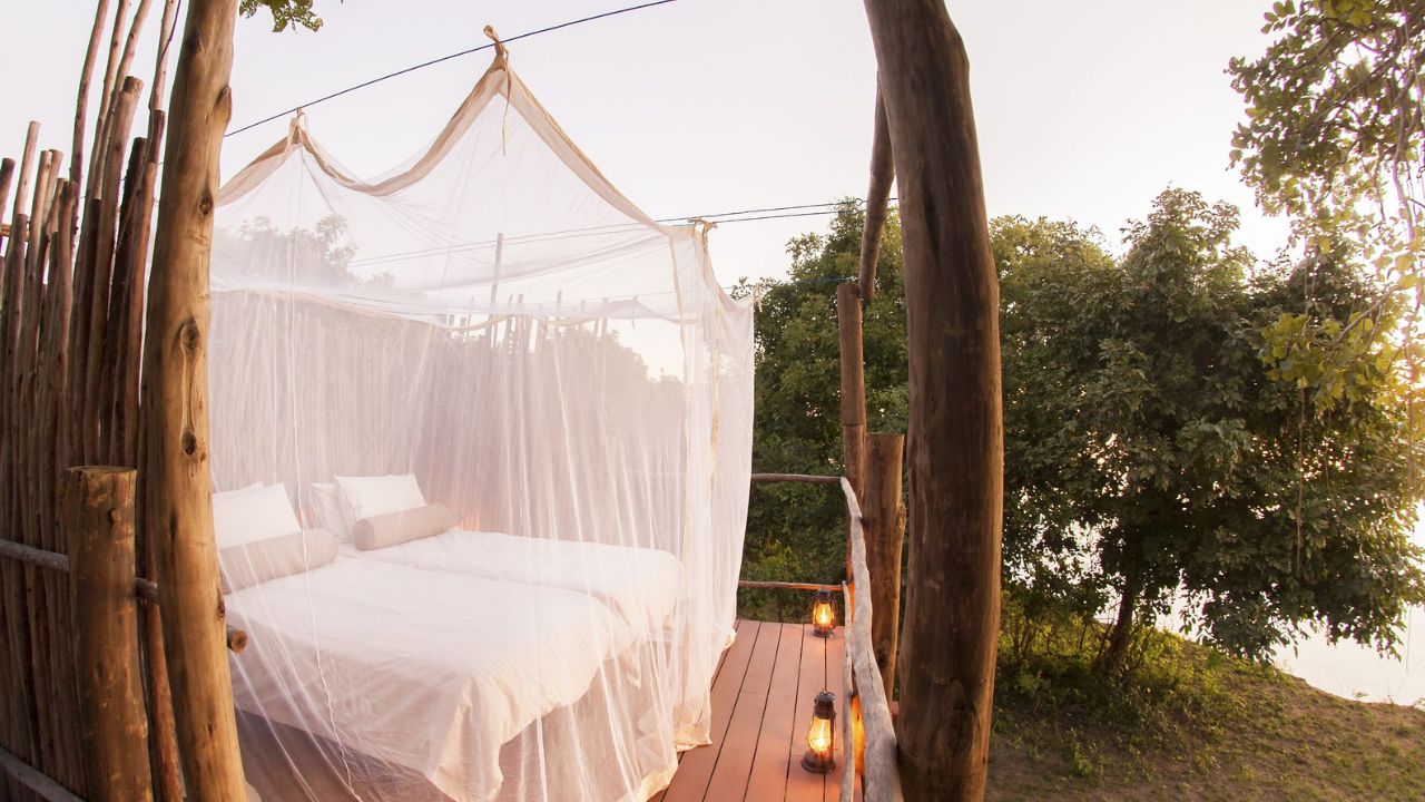 Private deck with outdoor bed and candlelit lamps overlooking river