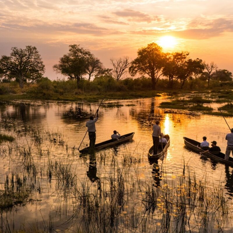 Canoe and walking safari at sunset along African river.