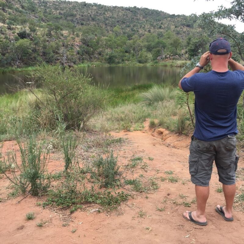 Tourist using binoculars viewing wildlife at Welgevonden Game Reserve.