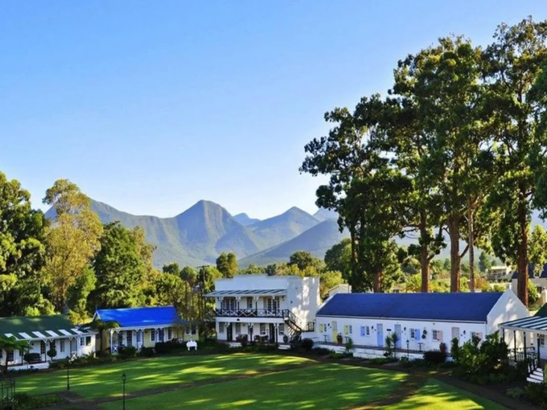 Tsitsikamma Village Inn viewed through flowers with mountains behind.
