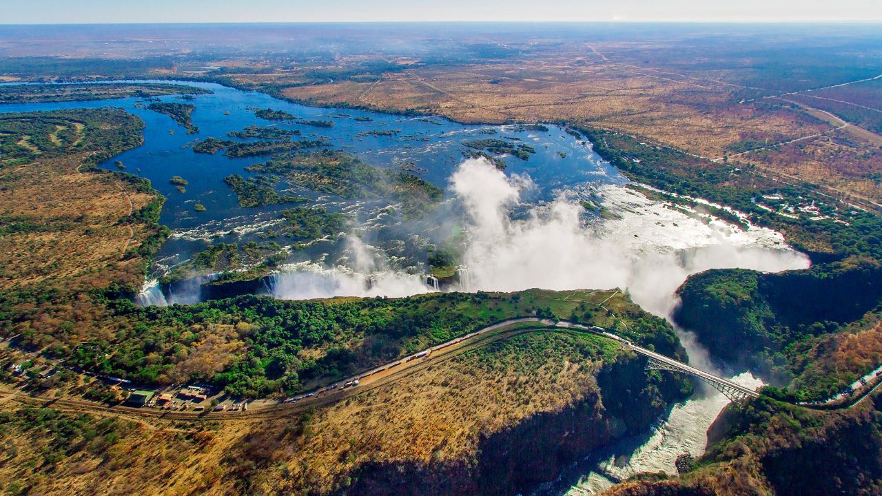 Victoria Falls as the dry season begins, with strong water flow and browning grass.